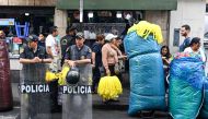 Police officers stand next to street vendors in downtown Lima on December 23, 2022. (Photo by Ernesto BENAVIDES / AFP)