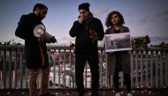 A woman holds a photographic portrait during tribute to Mohammad Moradi, an Iranian man who killed himself after jumping into the Rhone river to raise awareness about the situation of the Iranian people, in Lyon on December 27, 2022. (Photo by JEFF PACHOUD / AFP)