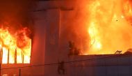 Fire burns around people on a ledge on the side of the Grand Diamond City hotel-casino in Poipet on December 29, 2022. (AFP)