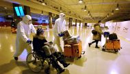 Workers wearing protective masks and suits help Chinese travellers leaving the arrival hall of Rome's Fiumicino International Airport on December 29, 2022 after being tested for the Covid-19 coronavirus. (Photo by Filippo Monteforte / AFP)