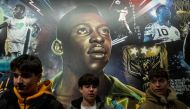 People pose in front of a mural of Brazilian soccer legend Pele while people mourn his death in Times Square in the Manhattan borough of New York City, U.S., December 29, 2022. REUTERS/Eduardo Munoz