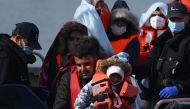 In this file photo taken on May 3, 2022 migrants, picked up at sea while attempting to cross the English Channel, are helped by a member of the UK Border Force to disembark from a boat, in the Marina at the Dover port, on the south-east coast of England. (Photo by Daniel LEAL / AFP)