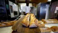 A baker shows freshly-baked baguettes at 