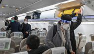 A passenger wearing a face shield and mask amid the Covid-19 pandemic boards a domestic flight at Shanghai Pudong International Airport in Shanghai on January 3, 2023. (Photo by HECTOR RETAMAL / AFP)