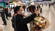 A passenger (R) receives a hug while leaving the arrival area of international flights at the Shanghai Pudong International Airport, in Shanghai on January 8, 2023.(Photo by Hector Retamal / AFP)