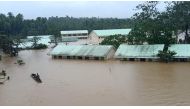This handout photo taken and released on January 10, 2023 from Jipapad Public Information Office shows a resident riding on a wooden boat as he paddles past submerged school buildings, due to floodings brought about by heavy rains in Jipapad town, Eastern Samar province, South of Manila. (Photo by Handout / Jipapad Public Information Office / AFP)