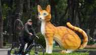 This photograph taken on January 16, 2023 shows a man riding a bicycle past a cat statue at Thong Nhat Park in Hanoi, ahead of the lunar new year. (Photo by Nhac NGUYEN / AFP)

