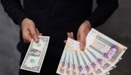 A currency dealer poses for a photo with a US one dollar bill and the amount being given when converting it into Iranian rials in an exchange shop in Tehran, Iran on December 25, 2022. Majid Asgaripour/WANA (West Asia News Agency) via REUTERS

