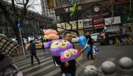 People walk on a street in Wuhan, in China's central Hubei province, on January 21, 2023. (Photo by Hector RETAMAL / AFP)