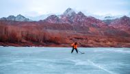 In this picture taken on January 20, 2023, an ice hockey player chases the puck on the frozen river Indus in Leh city, India. (Photo by Mohd Arhaan Archer / AFP)