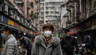 People walk down a street next to a local market in Wuhan, in China's central Hubei province, on January 23, 2023. (Photo by Hector RETAMAL / AFP)