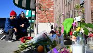 Inez Arakaki and her son Zachary offer prayers after bringing flowers to a makeshift memorial site in front of the Star Dance Studio in Monterey Park, California, on January 23, 2023, where 10 people were shot dead late on January 21, 2023. (Photo by Frederic J. Brown / AFP)