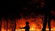 In this file photo taken on September 12, 2022 a firefighter stands in front of flames at a night wildfire in Saumos near Bordeaux, southwestern France. Photo by PHILIPPE LOPEZ / AFP