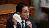 Japanese Prime Minister Fumio Kishida removes his face mask before his speech during a plenary session of the upper house of parliament in Tokyo on January 27, 2023. (Photo by Kazuhiro Nogi / AFP)