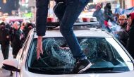A protestor steps on the windshield of a police vehicle, on the day of the release of a video showing police officers beating Tyre Nichols, the young Black man who died three days after he was pulled over while driving during a traffic stop by memphis police officers, in New York, U.S., January 27, 2023. REUTERS/Eduardo Munoz
