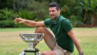 Serbia's Novak Djokovic celebrates with the Norman Brookes Challenge Cup trophy at the Government House a day after his victory against Greece's Stefanos Tsitsipas in the men's singles final match of the Australian Open tennis tournament in Melbourne on January 30, 2023. (Photo by Saeed Khan / AFP)