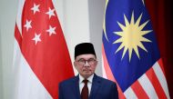 Malaysian Prime Minister Anwar Ibrahim stands in front of the Singapore (L) and Malaysian national flags during a signing ceremony at the Istana Presidential Palace in Singapore on January 30, 2023. (Photo by HOW HWEE YOUNG /AFP)