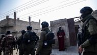 Syrian Kurdish Asayish security forces walks past a house during a raid against suspected Islamic State group fighters in Raqa, the jihadist group's former defacto capital in Syria, on January 29, 2023.  (Photo by Delil SOULEIMAN / AFP)