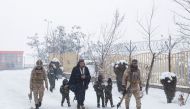Taliban soldiers with their children dressed in military uniforms and holding plastic weapons, walk on a snow-covered street on a snowy day in Kabul, Afghanistan, on January 29, 2023. REUTERS/Ali Khara