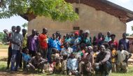 Musa Hasahya (C) pose for a picture with some of his wives, children and grandchildren outside their family home in Butaleja district in Eastern Uganda, on January 17, 2023. (Photo by Badru Katumba / AFP)