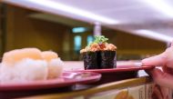 This picture shows plates of sushi on a conveyor belt at a sushi chain restaurant in Tokyo on February 3, 2023. (Photo by Philip Fong / AFP)