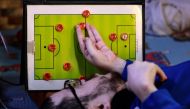 Amer Abo Nawas holds a board in the shape of a football field, used for explaining to his followers on the social media the plans of the coaches and the roles of the players on the field during a football match, at his home in Zarqa, 30km (18 miles) from Jordan's capital, Amman, on January 23, 2023. Photo by Khalil MAZRAAWI / AFP
