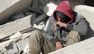 A Syrian man sits amidst the rubble as he waits for new about family members stuck under the wreckage in the town of Harim in Syria's rebel-held northwestern Idlib province on the border with Turkey, on February 8, 2023, two days after a deadly earthquake that hit Turkey and Syria. (Photo by Omar HAJ KADOUR / AFP)