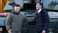 Ukraine's President Volodymyr Zelensky stands with Britain's Prime Minister Rishi Sunak as they wait to meet Ukrainian troops being trained to command Challenger 2 tanks at a military facility in Lulworth, Dorset in southern England on February 8, 2023.  (Photo by Andrew Matthews / POOL / AFP)