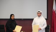 Assistant Undersecretary in the Ministry of Social Development and Family, Ghanem Mubarak Al Kuwari (right), and Executive Director of the Administrative and Financial Sector in Doha Institute for Graduate Studies, Iman Al Sulaiti, exchanging documents after signing the agreement.