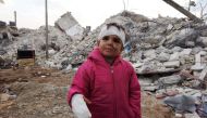 Musa Hmeidi, a Syrian child who was pulled out alive from under the rubble of a collapsed building on February 10, 2023, four days after a deadly earhquake hit the area, in the rebel-held town of Jindayris, in the rebel-held part of Aleppo province, is pictured in front of the building from which he was rescued. (Photo by Bakr ALKASEM / AFP)