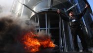 A Lebanese protester flashes the V-sign for victory and shouts slogans as others vandalise banks in Beirut on February 16, 2023 (Photo by Joseph Eid / AFP)