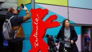 A man makes a photograph as a woman passes the logo of the upcoming Berlinale 73rd International Film Festival in Berlin on February 15, 2023. (Photo by David GANNON / AFP)