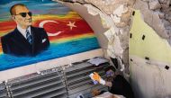Turkish optician Cuneyt Eroglu, 45-year-old, collects glasses and other stuff from his collapsed shop in Antakya on February 18, 2023. (Photo by Sameer Al-DOUMY / AFP)
