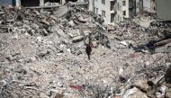 A man walks atop the rubble of collapsed buildings in Kahramanmaras, southeastern Turkey, on February 18, 2023. (Photo by Zein Al Rifai / AFP)