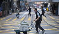 This photo taken on February 21, 2023 shows a vendor crossing a street in Central district of Hong Kong. - Hong Kong痴 finance chief unveiled a HK$761 billion ($97 billion) budget on February 22, plunging into the coffers to foot the bill for the recession-hit city痴 post-Covid recovery. (Photo by Peter PARKS / AFP)