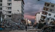 A man walks among collapsed buildings, a day after a 6.4-magnitude earthquake struck the region, in the coastal city of Samandag on February 21, 2023. Photo by BULENT KILIC / AFP
