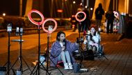 The photo taken on February 20, 2023 shows outdoor livestreamers singing and chatting with the audiences through their mobile phones on an overpass bridge at night in Guilin, in southern China's Guangxi province. Photo by Jade GAO / AFP