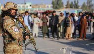 A Taliban security personnel stand guard as Afghan people wait to cross into Pakistan, near the closed Torkham gate at the Torkham border crossing between Afghanistan and Pakistan, in Nangarhar province on February 23, 2023. (Photo by Shafiullah KAKAR / AFP)