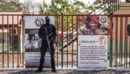 A military official stands next to a banner reflecting the face of Thomas Sankara in Ouagadougou on February 23, 2023, ahead of the reburial ceremony of Thomas Sankara's remains alongside his twelve companions, killed on October 15, 1987. (Photo by OLYMPIA DE MAISMONT / AFP)