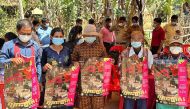 This picture released by Cambodia's Communicable Disease Control Department (CDCD) on February 23, 2023, shows villagers posing with posters about H5N1 virus threats, in Prey Veng province. Photo by Handout / Cambodia's Communicable Disease Control Department / AFP