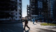 A woman walks next to a residential building, destroyed during an attack, in Borodyanka on February 23, 2023, amid Russia's military invasion on Ukraine. Photo by Dimitar DILKOFF / AFP 