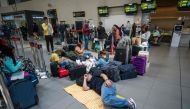 People lie on the floor after their flights were cancelled at the El Dorado international airport in Bogota on February 28, 2023. (Photo by Juan Barreto / AFP)