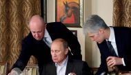 Evgeny Prigozhin (L) assists Russian Prime Minister Vladimir Putin during a dinner with foreign scholars and journalists at the restaurant Cheval Blanc on the premises of an equestrian complex outside Moscow November 11, 2011. REUTERS/Misha Japaridze/File Photo
