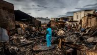 A boy stands in the remains of a burnt house in a residential area in Plumpang, north Jakarta on March 4, 2023, after a fire at a nearby state-run fuel storage depot run by energy firm Pertamina. (Photo by Aditya Aji / AFP)