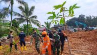 This handout picture taken on March 8, 2023 and released on March 9, 2023 by ministry of communication and information shows rescue team evacuate the body of a victim that was found buried by a landslide at Pangkalan village, in Natuna Islands. (Photo by Handout / Natuna ministry of communication / AFP)