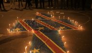 In this file photo taken on December 07, 2022 flags of the Democratic Republic of Congo are surrounded by candles in Beni during a prayer vigil in remembrance of the victims of the ungoing unrest in the East of the country. (Photo by Sébastien KITSA MUSAYI / AFP)
