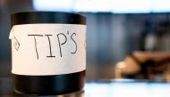 A tip jar sits on a countertop at a store in Washington, DC, on March 17, 2023. (Photo by Stefani Reynolds / AFP)