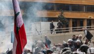 Security offices in the background watch as retired Lebanese army and security forces veterans gather to protest outside the government palace headquarters in the centre of Beirut on March 22, 2023, demanding inflation-adjustments to their pensions. (Photo by JOSEPH EID / AFP)