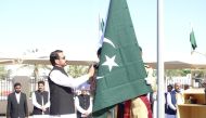 Pakistan Ambassador to Qatar H E Muhemmed Aejaz (right) hoisting the national flag during the ceremony to mark the Pakistan National Day as officials and guests look on.