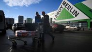 Men walk with a cart loaded with purchases on a parking lot of a Leroy Merlin DIY store in the Moscow region, some 50 km off Moscow, on March 24, 2023. (Photo by NATALIA KOLESNIKOVA / AFP)
